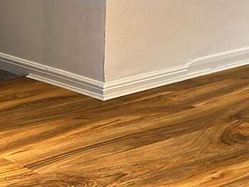 Close-up of new wood-effect flooring finished neatly against white skirting board