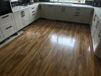 Wood-effect flooring laid through a grey shaker kitchen